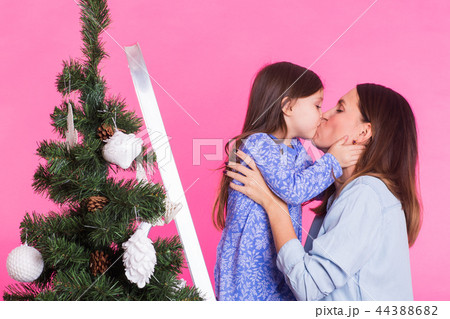 Christmas of young mom and her daughter with Christmas tree on pink background Christmas of young mom and her daughter with Christmas tree on pink background 44388682
