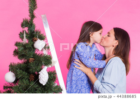 Young mom and her daughter with Christmas tree on pink background 44388685