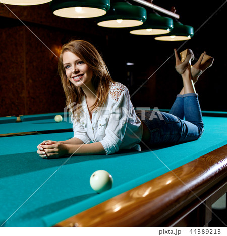 Young woman lying on the green billiard table. 44389213
