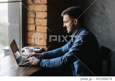 Man with a beard uses a laptop in a cafe 44398670