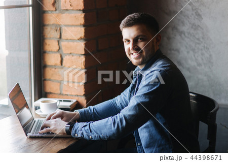 Man with a beard uses a laptop in a cafe 44398671
