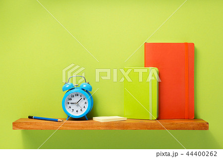 notepad and alarm clock on shelf at wall  44400262