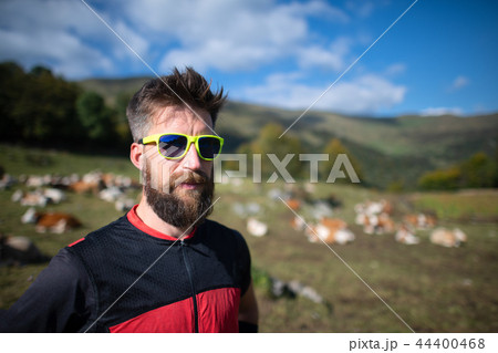 Sporty man with beard near a cows pasture 44400468