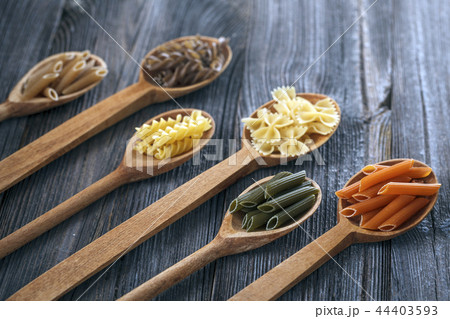 A set of raw pastas on spoons on a wooden table A set of raw pastas on spoons on a wooden table 44403593