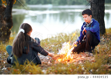 boy and girl sitting on river Bank, make a fire boy and girl sitting on river Bank, make a fire 44404535