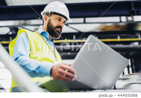 A portrait of an industrial man engineer with laptop in a factory, working. 44405088