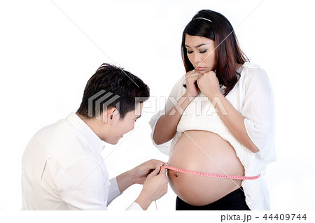 Husband measuring his pregnant wife's belly with tape Husband measuring his pregnant wife's belly with tape 44409744