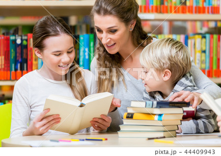 Teacher with her class visiting the library reading books 44409943