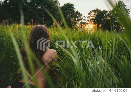 Young brunette woman enjoying the lying on green fresh looking on sunset. 44410105