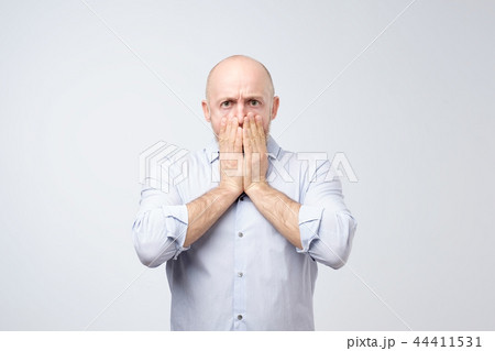 Portrait of a shocked young man covering his mouth with hands Portrait of a shocked young man covering his mouth with hands 44411531