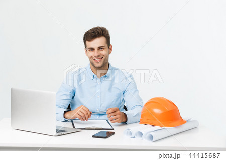 Happy young construction workers in hard hats on a white background. Happy young construction workers in hard hats on a white background. 44415687