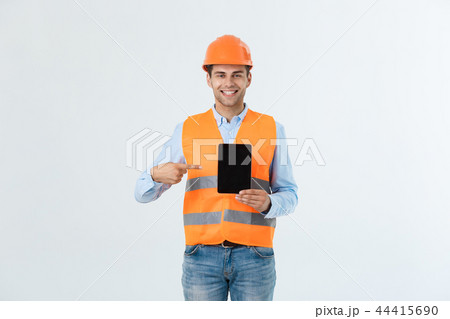 Happy young construction workers in hard hats on a white background. Happy young construction workers in hard hats on a white background. 44415690