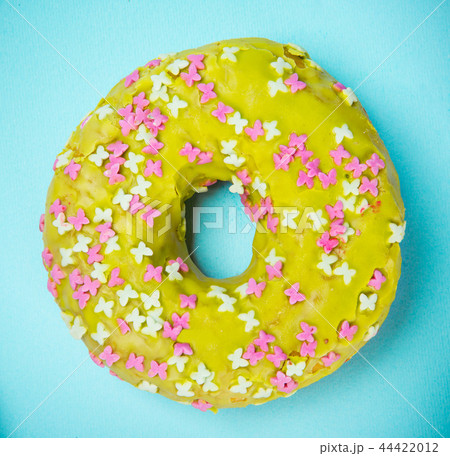 Glazed donut with colorful sprinkles on blue pastel background. 44422012