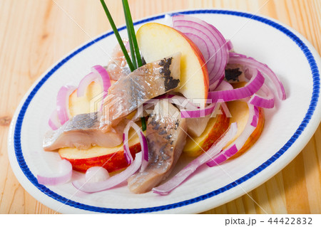 Slices of mild-cured herring with potatoes and onions served on plate 44422832