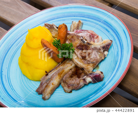 Grilled lamb with mashed jacket potato and mustard at plate with carrots 44422891