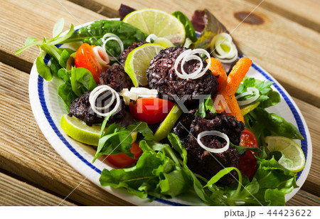 Fried tasty blood sausage with lettuce and lemon, served at plate 44423622