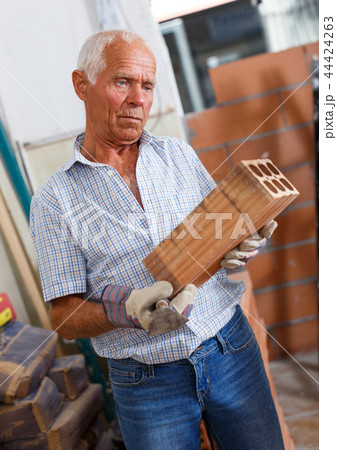 Man inspecting brick for installing wall Man inspecting brick for installing wall 44424263