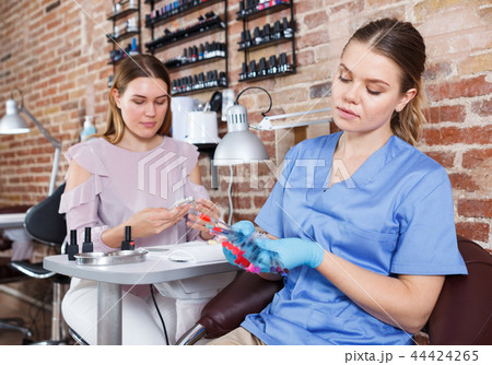 Manicurist showing color samples of nail polish in nail salon Manicurist showing color samples of nail polish in nail salon 44424265