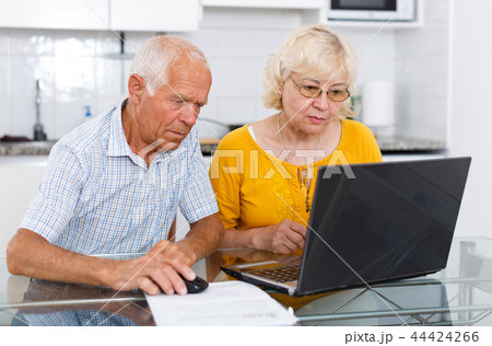 Mature man and woman discussing while looking at laptop together Mature man and woman discussing while looking at laptop together 44424266