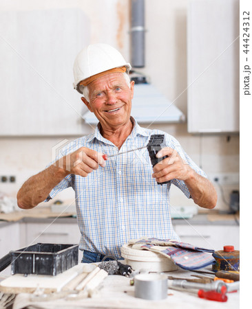Man in hardhat engaged in renovation work Man in hardhat engaged in renovation work 44424312