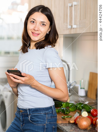 Young girl housewife using phone at home kitchen 44424706