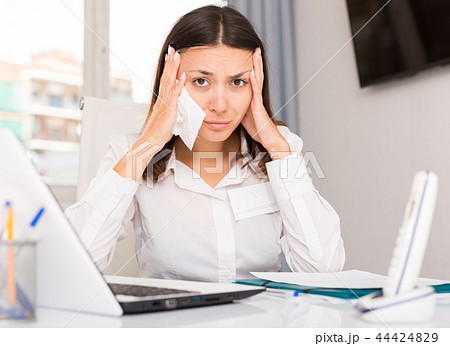Upset woman crying and holding napkin at laptop at the office Upset woman crying and holding napkin at laptop at the office 44424829