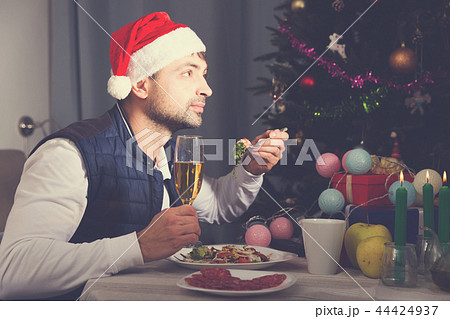 Man in hat having christmas dinner with champagne Man in hat having christmas dinner with champagne 44424937
