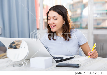 Young woman student working with laptop and pen at table 44425010
