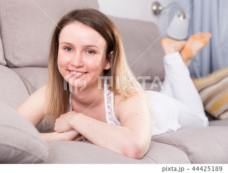 Cheerful girl is lying on sofa and playful posing 44425189