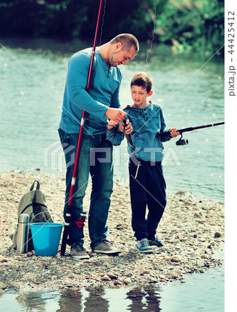 Portrait of father and son fishing with rods Portrait of father and son fishing with rods 44425412