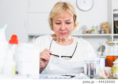 Mature woman with medicines and bills 44426000