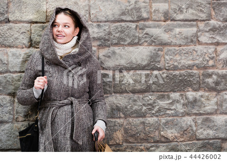 cheerful female in coat hood near wall 44426002
