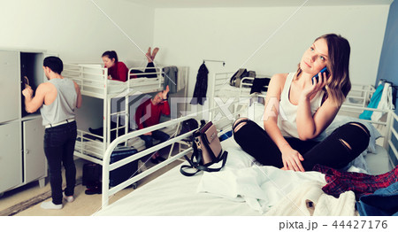 Woman talking on phone on bed in hostel Woman talking on phone on bed in hostel 44427176