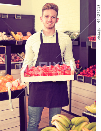 Man seller moving box of persimmons Man seller moving box of persimmons 44427218