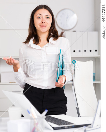 Girl manager holding clipboard and welcoming to office Girl manager holding clipboard and welcoming to office 44427258