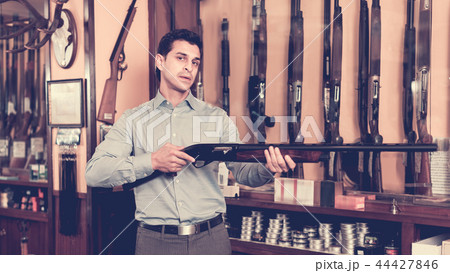 Handsome adult male in hunting shop with rifle in hands 44427846