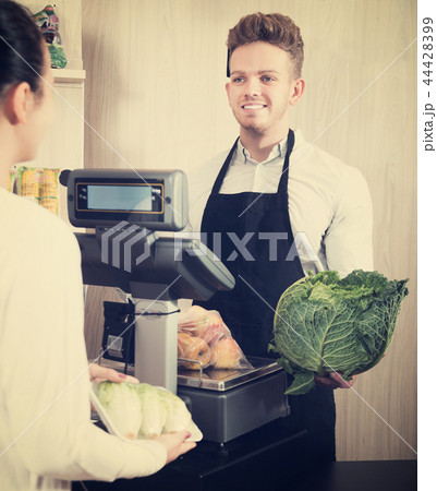 Seller assisting customer to weigh purchases Seller assisting customer to weigh purchases 44428399