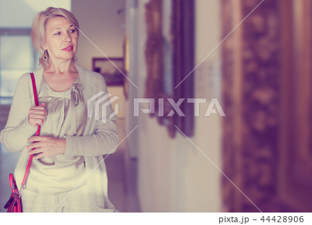 Mature woman standing in art museum near the painting in baguette Mature woman standing in art museum near the painting in baguette 44428906