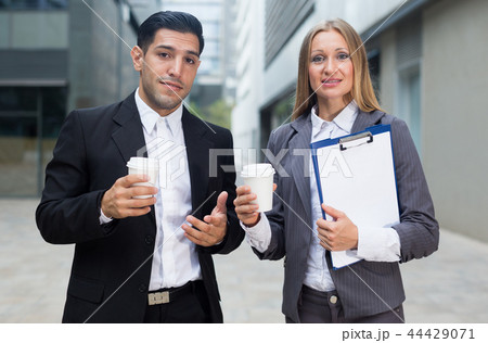 Businessman and his woman colleague in suit are standing with folder and coffee 44429071