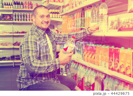 man choosing mineral water in grocery. man choosing mineral water in grocery. 44429675