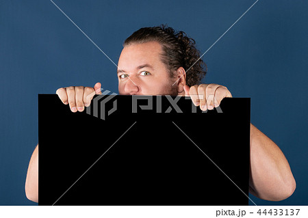 Funny fat man in a bright striped shirt holding a black writing board Funny fat man in a bright striped shirt holding a black writing board 44433137