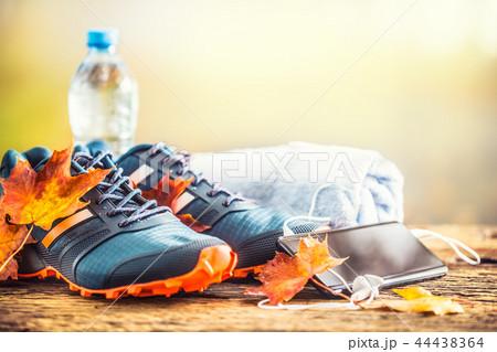 Blue sport shoes and water laid on a wooden board. 44438364