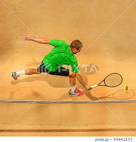 The one jumping player, caucasian fit man, playing tennis on the earthen court The one jumping player, caucasian fit man, playing tennis on the earthen court 44441555