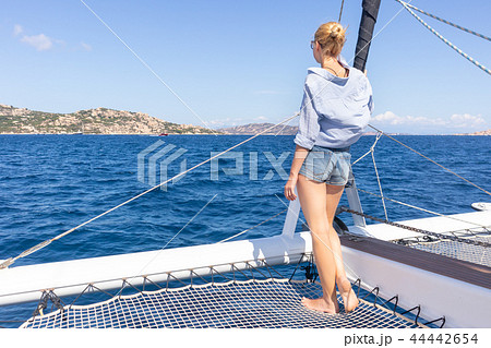 Woman relaxing on a summer sailin cruise, sitting on a luxury catamaran, standing in Maddalena 44442654