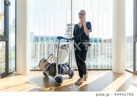 Casual woman on airport terminal talking on the cell phone, waiting for flight departure with Casual woman on airport terminal talking on the cell phone, waiting for flight departure with 44442700