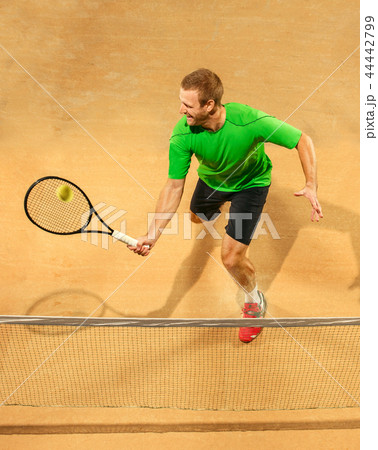 The one jumping player, caucasian fit man, playing tennis on the earthen court 44442799