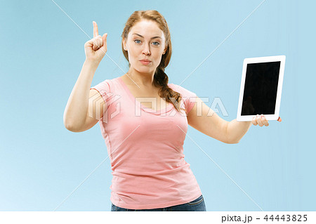 Portrait of a confident casual girl showing blank screen of laptop isolated over blue background 44443825
