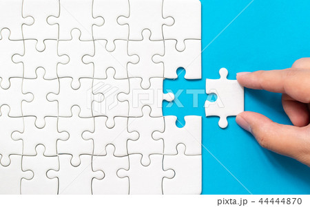 Hand putting piece of white jigsaw puzzle 44444870