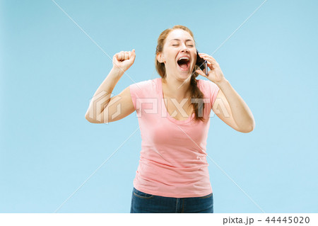 Young beautiful woman using mobile phone studio on blue color background Young beautiful woman using mobile phone studio on blue color background 44445020