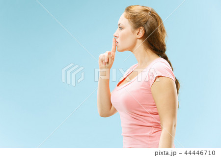 The young woman whispering a secret behind her hand over blue background The young woman whispering a secret behind her hand over blue background 44446710